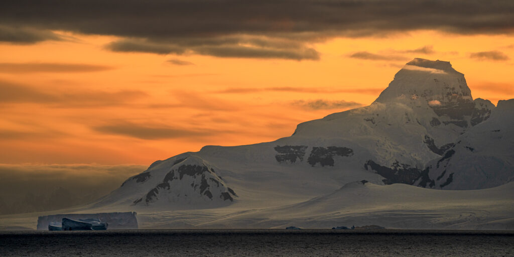 Sunset over the Antarctic Peninsula. The ractangular iceberhg at the bottom left is bigger than a foorball stadium.