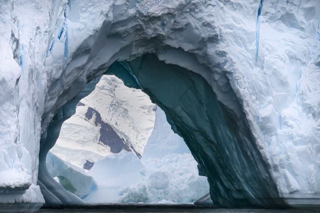 A wind carved iceberg floats near the Antarctic Peninsula. The darker blue ice is older than the lighter ice because it is compressed and contains fewer air bubbles.
