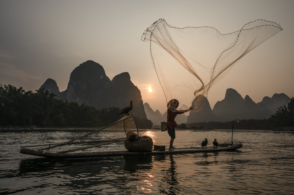 A cormarant fisherman throws a net in Erhai Lake in Yunnan province, China.