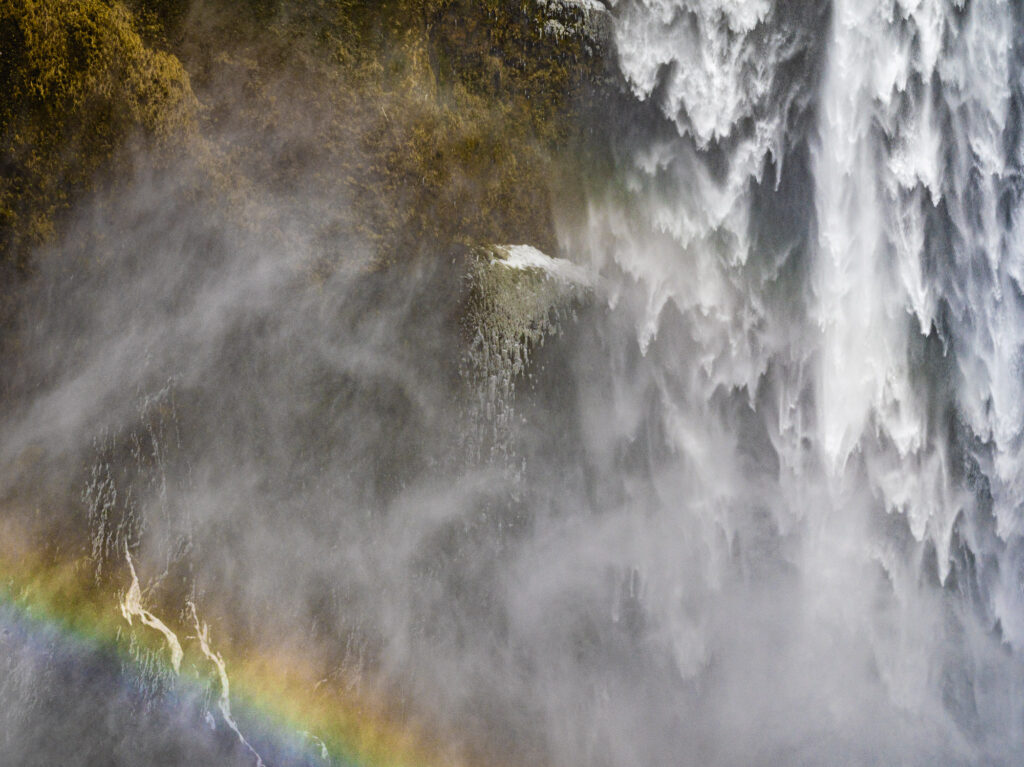 A rainbow forms in the mist of a waterfall in Iceland.