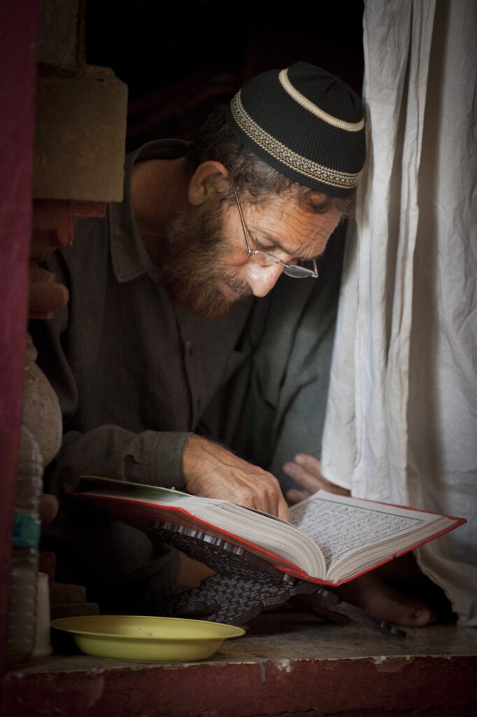 A Muslim man quietly reads the Holy Koran at Nizamuddin Shrine in New Delhi.