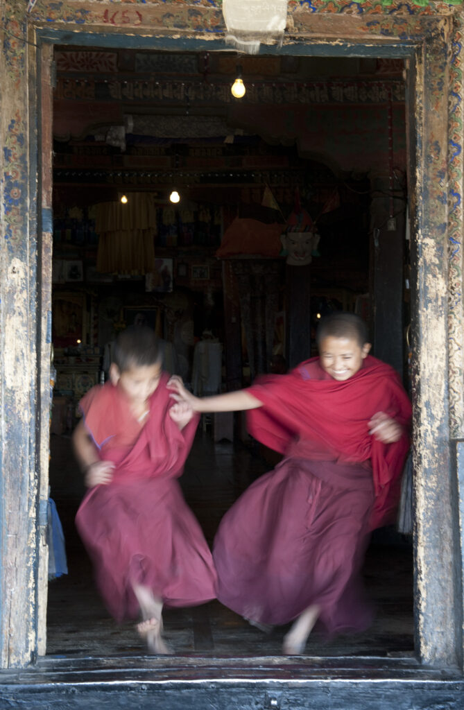 Young monks run to play after attending morning prayer in a Buddhist monestary in Ladakh.