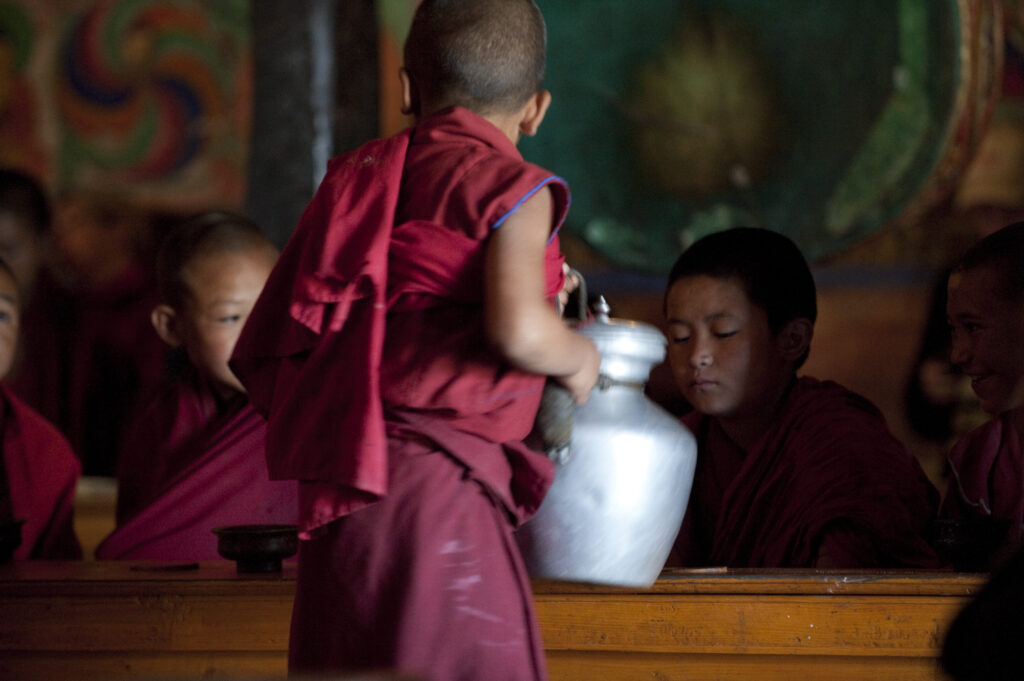 Young monks drink tea during morning prayer in a Buddhist monestary in Ladakh.