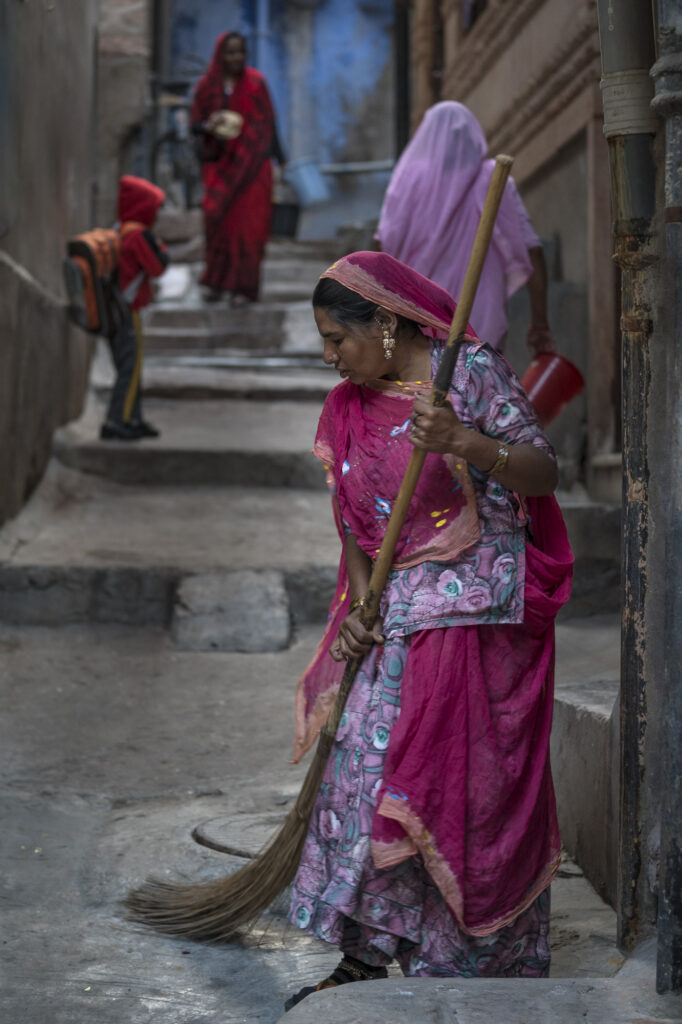 A woman sweeps the street outsode her home in Johdpur.