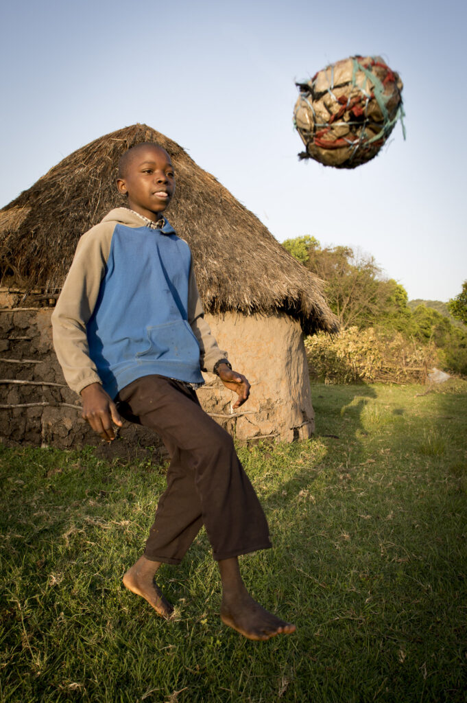 A Maasai boy plays with a soccer ball bade from discarded plastic bags.