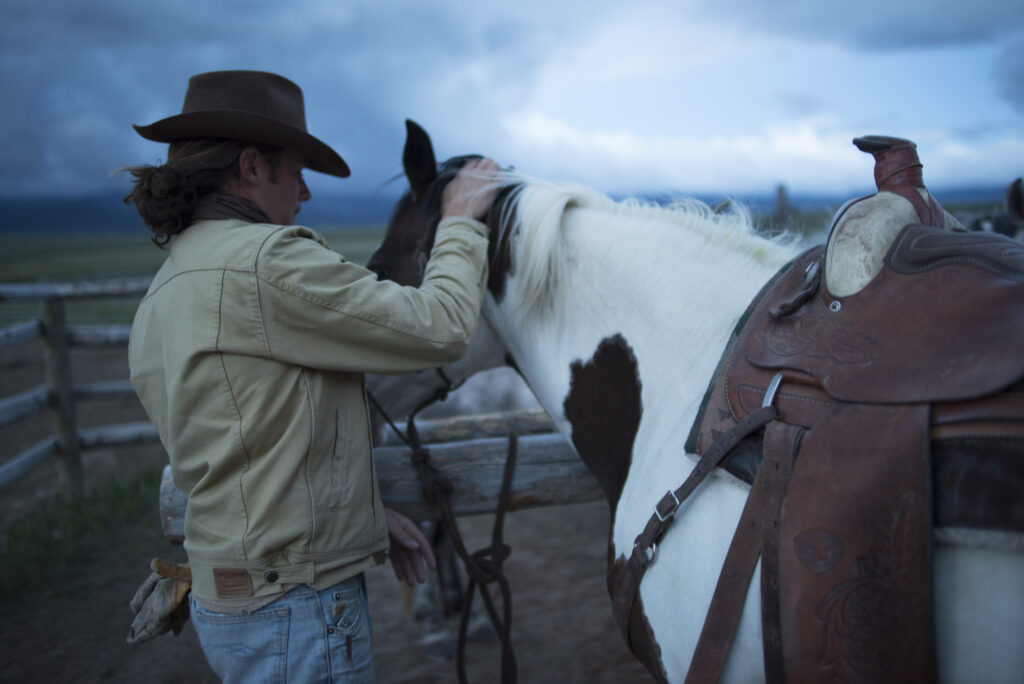 A cowboy saddles his horse before a long day.