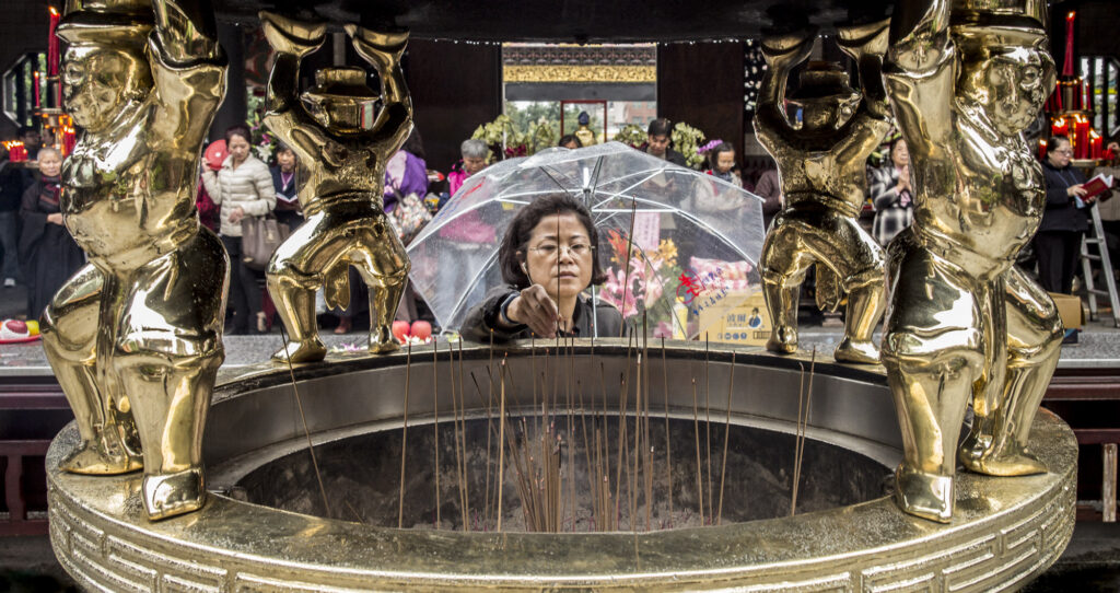 A worshippers light incense on a rainy day at Longshan Temple, Taipei, Taiwan