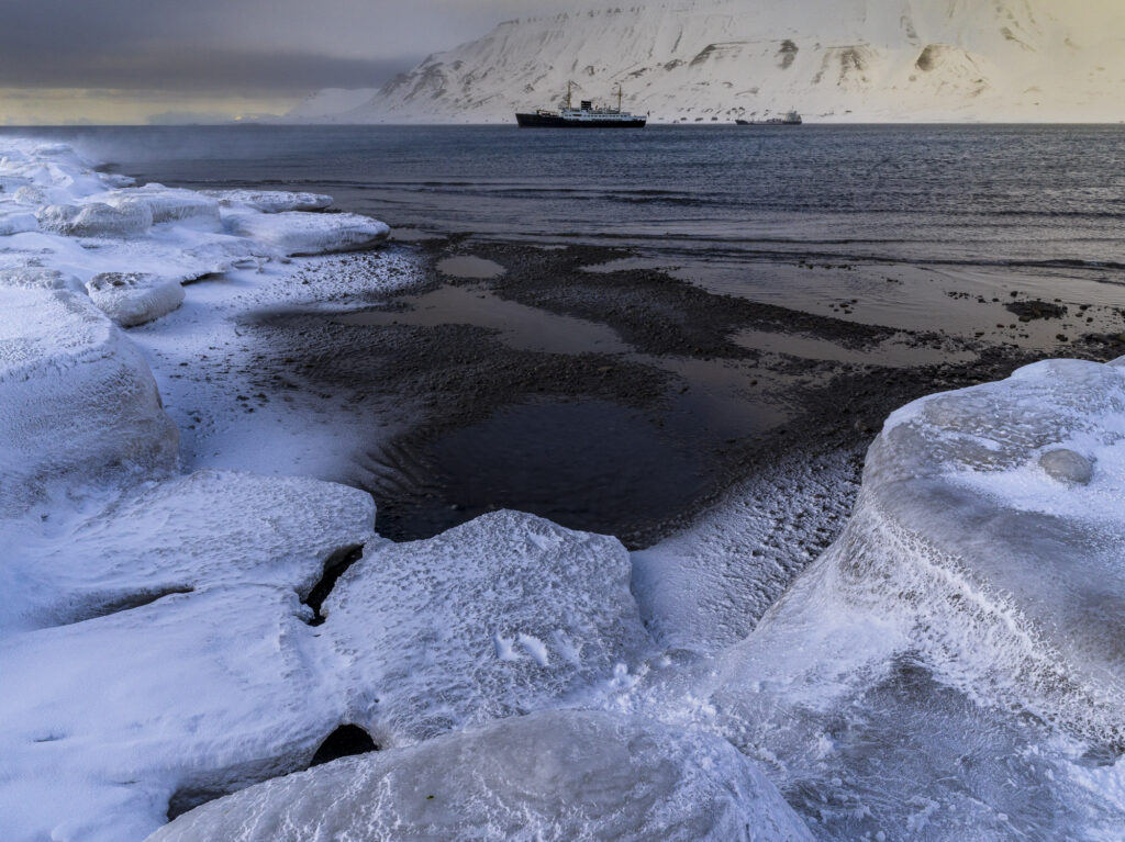 Boats in Longyearbyen harbor in Svalbard with ice in the foreground