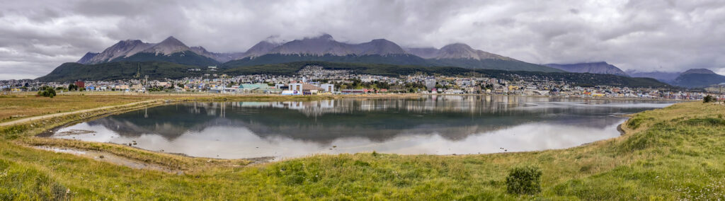 The city of Ushiaia reflected in a lake with the Martial mountains in the background.