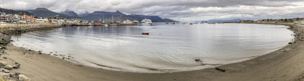 The city of Ushiaia reflected in a lake with the Martial mountains in the background.